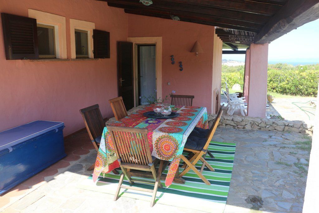 Un área de comedor al aire libre con una mesa para dos, un banco de madera y un muro de piedra.