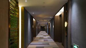 Un pasillo largo y estrecho con piso estampado, paneles de madera en las paredes y picaportes iluminados.