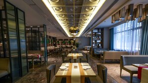 Un restaurante moderno con un espacio central para comer, con mesas cubiertas con manteles a rayas y sillas alrededor.