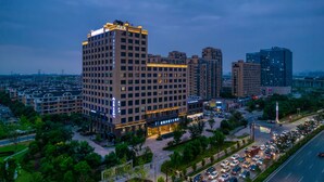 Un hotel moderno de gran altura con varios pisos, un patio central y una calle concurrida al fondo.