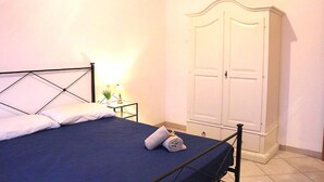 A bedroom with a bed, a nightstand, a lamp, and a wardrobe. - Le Perle del Centro (Santa Teresa di Gallura)