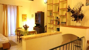A cozy living room with a dining area, a bookshelf, and a staircase. - Casa di Anna (Santa Teresa di Gallura)