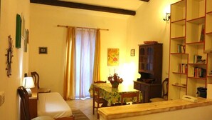 A compact room with a bed, a small dining table with chairs, a bookshelf, and a cabinet. - Casa di Anna (Santa Teresa di Gallura)