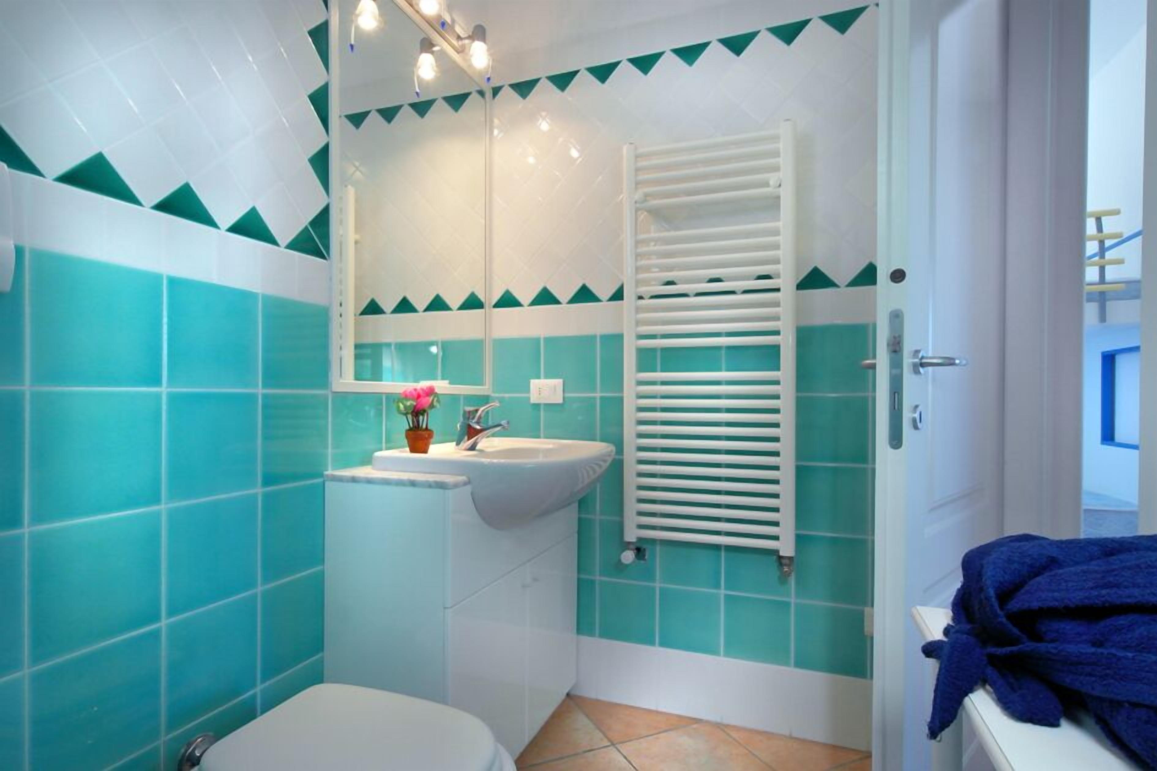 Une salle de bain avec un lavabo blanc, des toilettes blanches et un porte-serviettes.