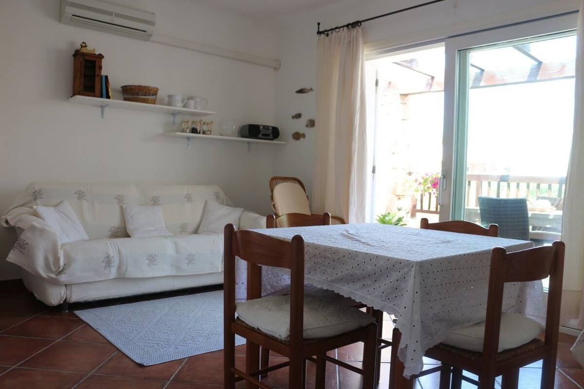 A dining area with a table and chairs, a white sofa, and a window with curtains.