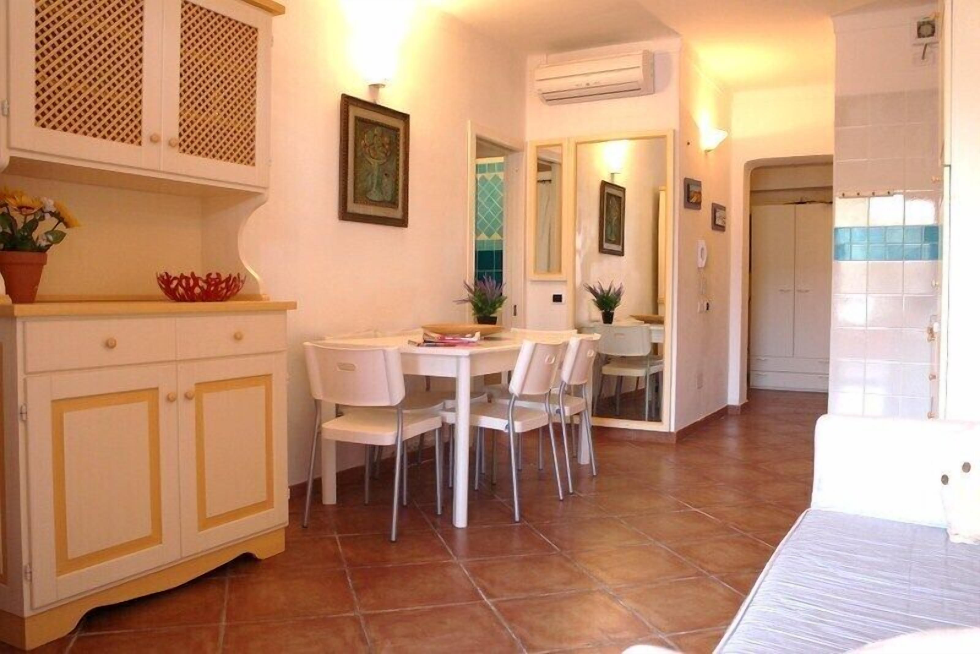 Un comedor con una mesa y sillas blancas, un armario con diseño de celosía y suelo de baldosas.