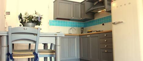 Una cocina con gabinetes grises, un refrigerador blanco y un salpicadero de azulejos azules.