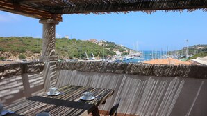 Eine Terrasse mit Esstisch, die auf einen Yachthafen und eine hügelige Landschaft blickt.