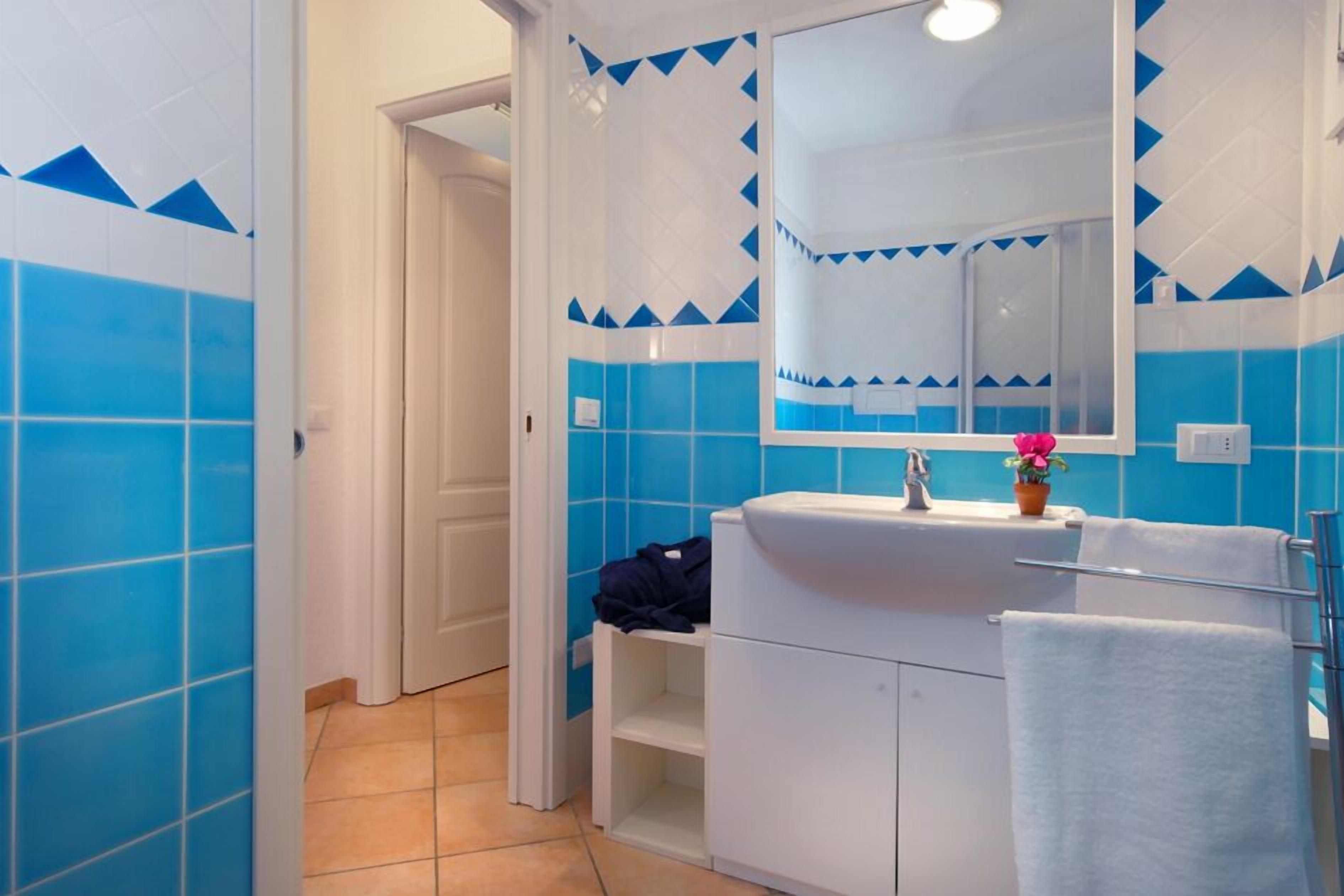 A bathroom with blue and white tiles, a white sink, a mirror, and a towel rack.