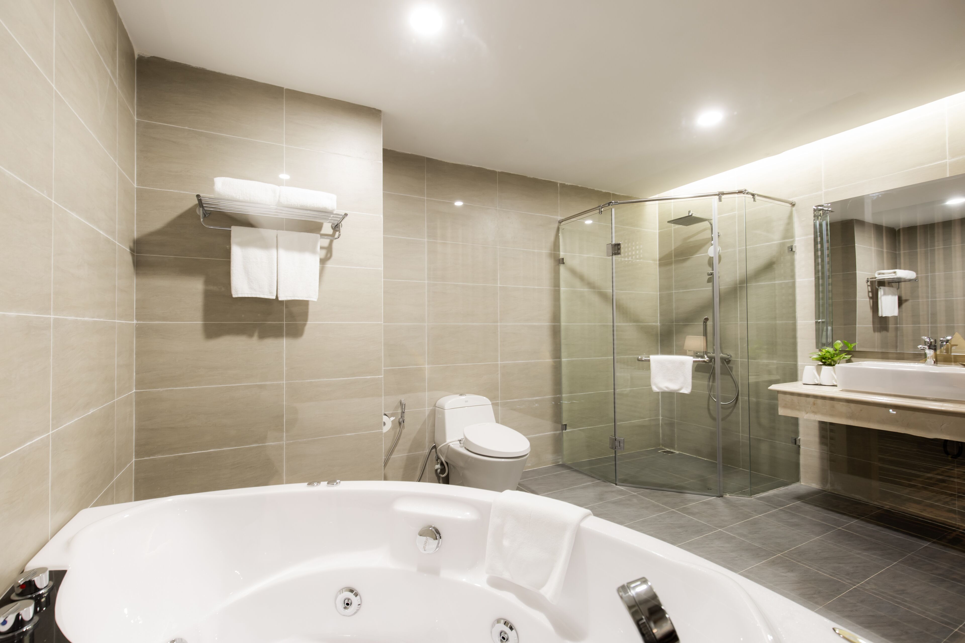 A modern bathroom with a glass-enclosed shower, a freestanding bathtub, and a vanity with a mirror.