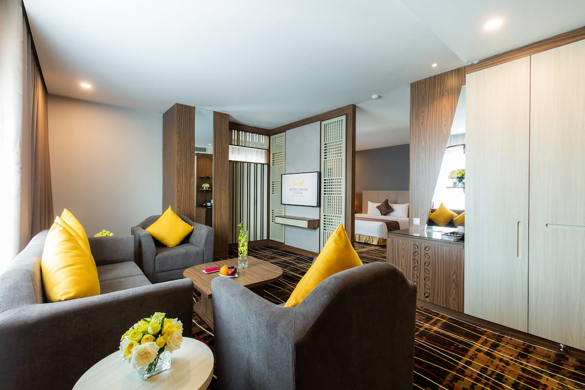 Une chambre d’hôtel moderne comprenant un canapé, une petite table basse, un téléviseur et un coin cuisine.