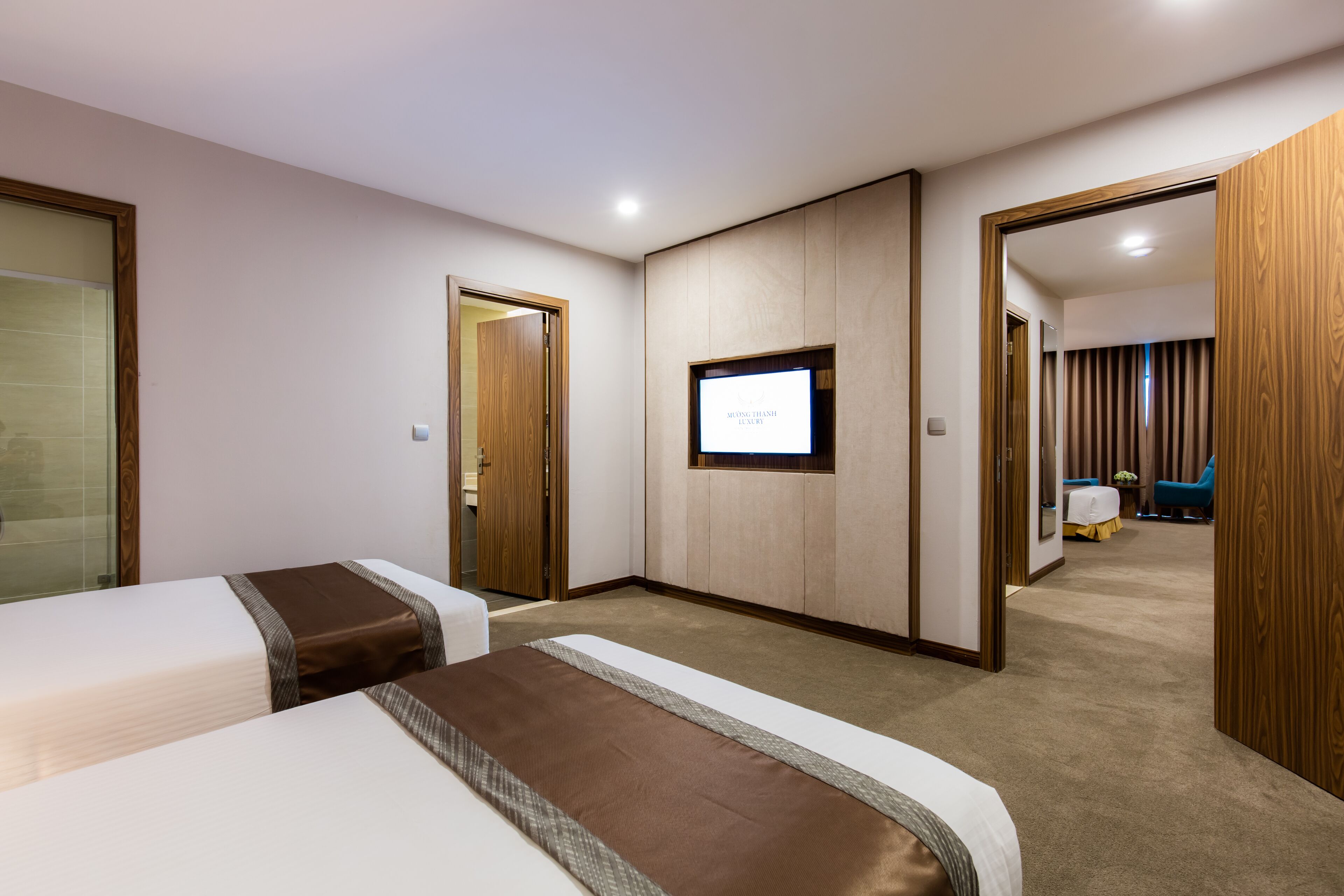 A hotel room with two beds, a television, and a wooden wardrobe.