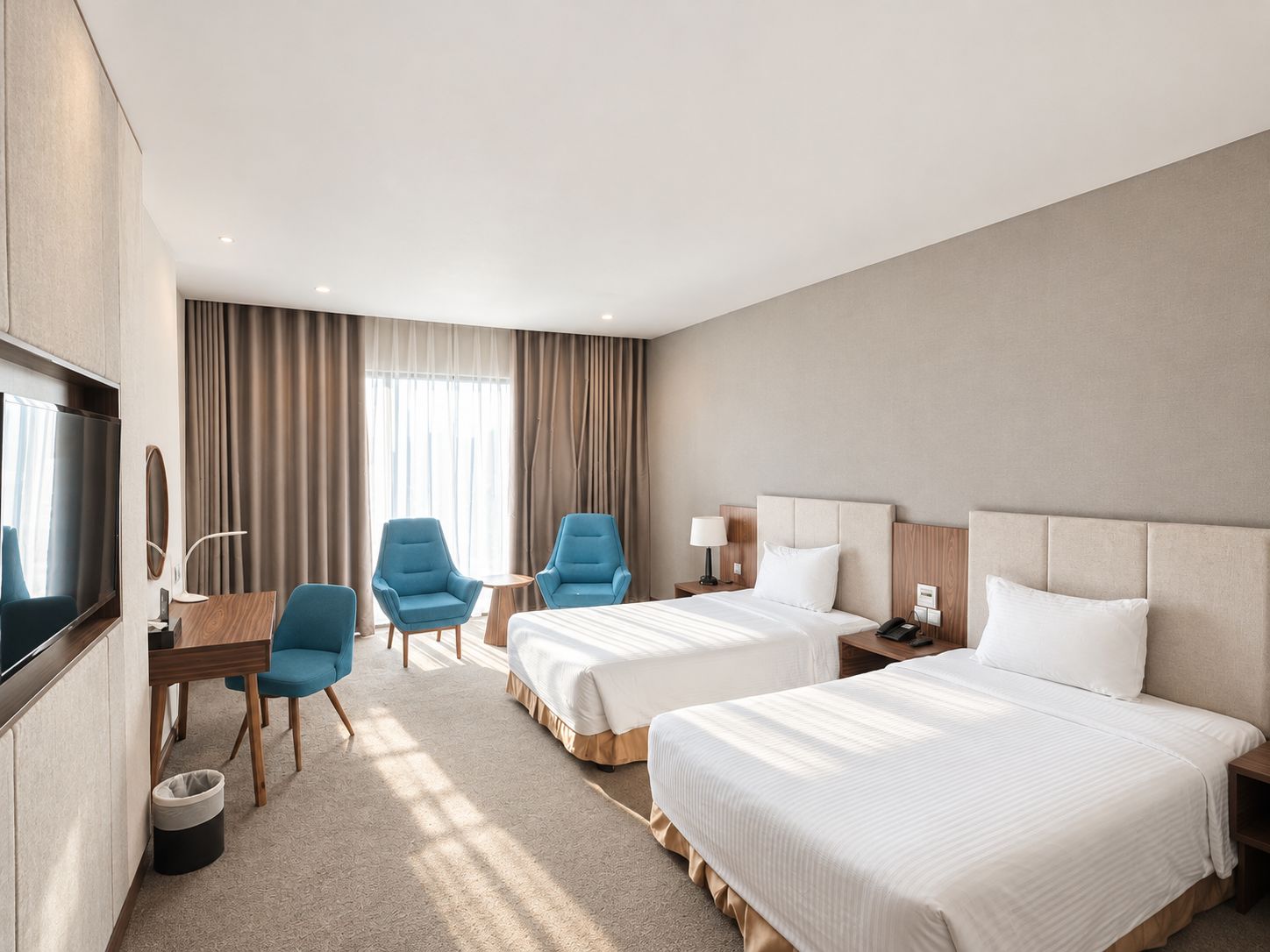 Une chambre d’hôtel avec deux lits, un bureau, deux chaises, une télévision et une fenêtre avec des rideaux.