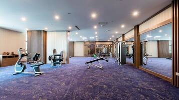 A gym with exercise equipment, a blue carpet, and a large mirror.