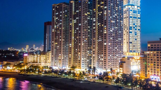 A high-rise hotel with multiple floors, a prominent illuminated sign, and a beachfront location. - Muong Thanh Luxury Vien Trieu Hotel (Bac Nha Trang)