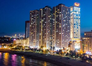 A high-rise hotel with multiple floors, a prominent illuminated sign, and a beachfront location.