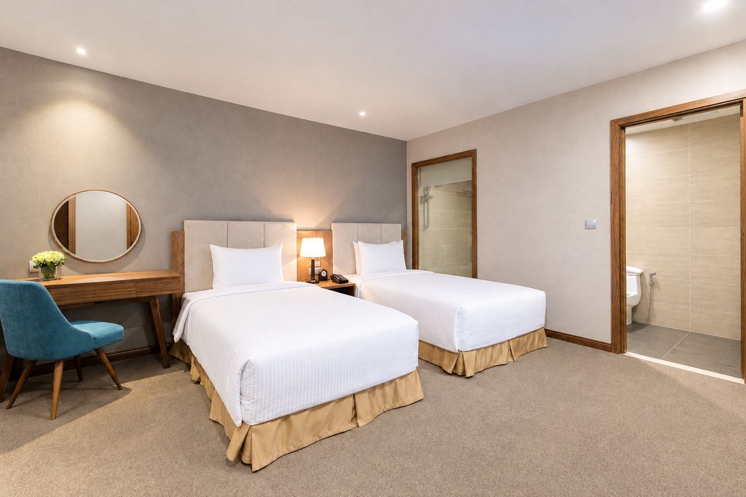 Une chambre d’hôtel avec deux lits, un bureau, une chaise, un miroir et un espace douche.