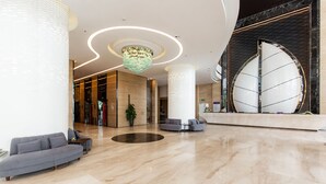 A spacious lobby with a modern design, featuring a large reception desk, seating area, and a decorative chandelier. - Muong Thanh Luxury Vien Trieu Hotel (Bac Nha Trang)