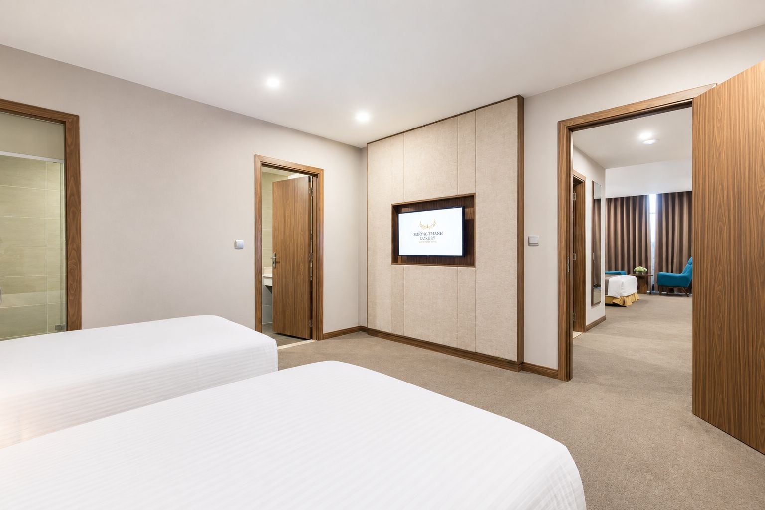 Une chambre d’hôtel avec deux lits, une télévision et une vue sur la chambre voisine.