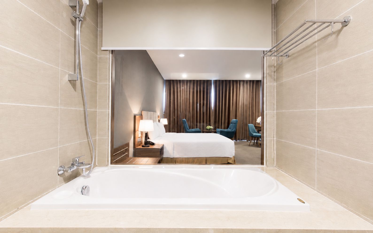 Une salle de bain d’hôtel moderne, dotée d’une grande baignoire, d’une douche et d’un coin salon avec un lit et des fauteuils.