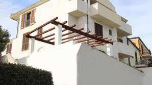 Un bâtiment blanc doté d’un toit incurvé, de balcons en bois et d’une petite fenêtre avec des volets.