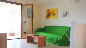 Une pièce avec un canapé vert, une table en bois et un tableau accroché au mur.