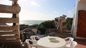 Un patio exterior con mesa y sillas, con vista al mar.