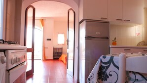 Una cocina con estufa, horno, refrigerador y una mesa con mantel estampado.