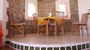 Una habitación con paredes de piedra, una mesa redonda y cuatro sillas de mimbre.