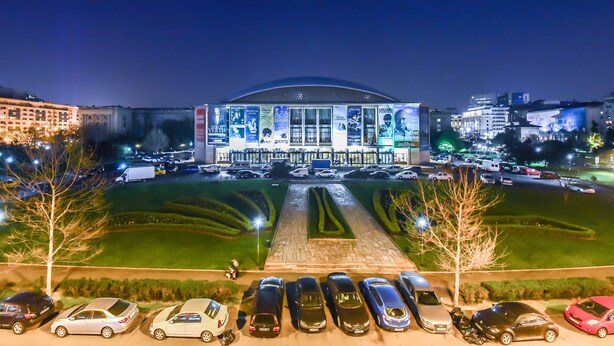 A large, illuminated building with a central dome and multiple banners. - Grand Accomodation Apartments (Bucharest)