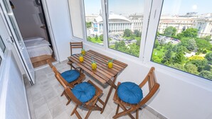 A room with a large window, a dining table with chairs, and a view of a cityscape. - Grand Accomodation Apartments (Bucharest)