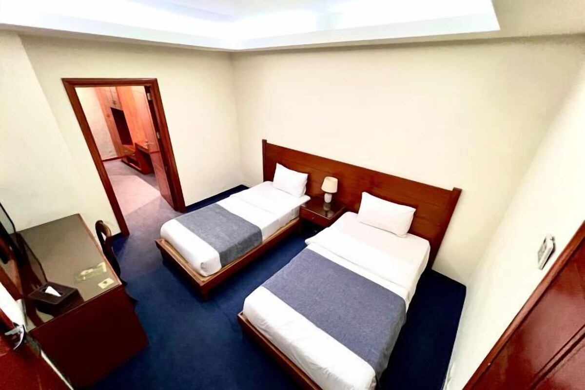 A hotel room with two beds, a small desk with a mirror, and a door leading to a bathroom.