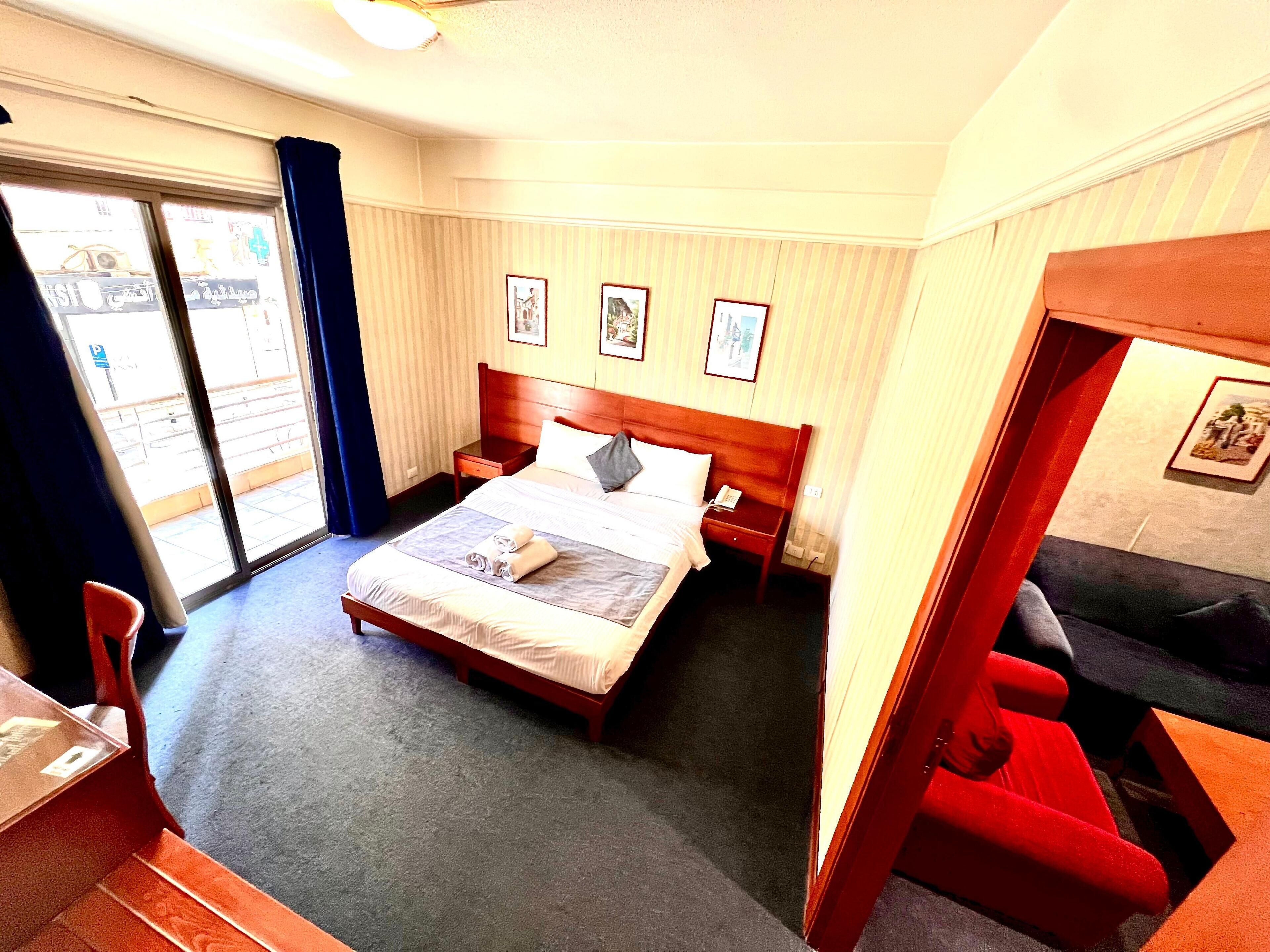 A hotel room with a bed, bedside tables, a desk, and a chair.