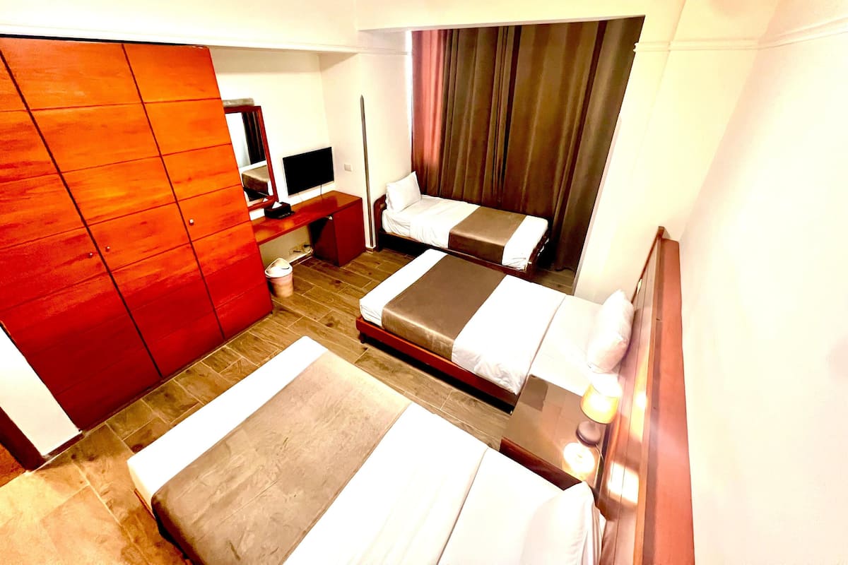 A hotel room with two beds, a TV, a desk, and a wardrobe.