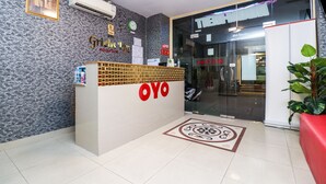A reception desk with a logo, a clock, and a plant. - OYO 131 Griebs Inn (Pattaya)