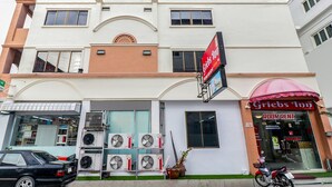 A hotel with a prominent Griebs Inn sign, multiple air conditioning units outside, and a motorcycle parked in front. - OYO 131 Griebs Inn (Pattaya)