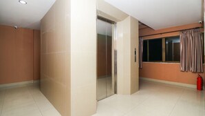 A spacious room with a large window, a sliding door, and a fire extinguisher. - OYO 131 Griebs Inn (Pattaya)
