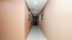 A hallway with light-colored walls and a tiled floor, leading to a door at the end. - OYO 131 Griebs Inn (Pattaya)