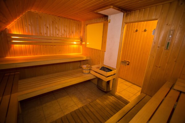 A wooden sauna with benches, a bench with a bucket, and a door. - Buitengoed Fredeshiem (De Bult)