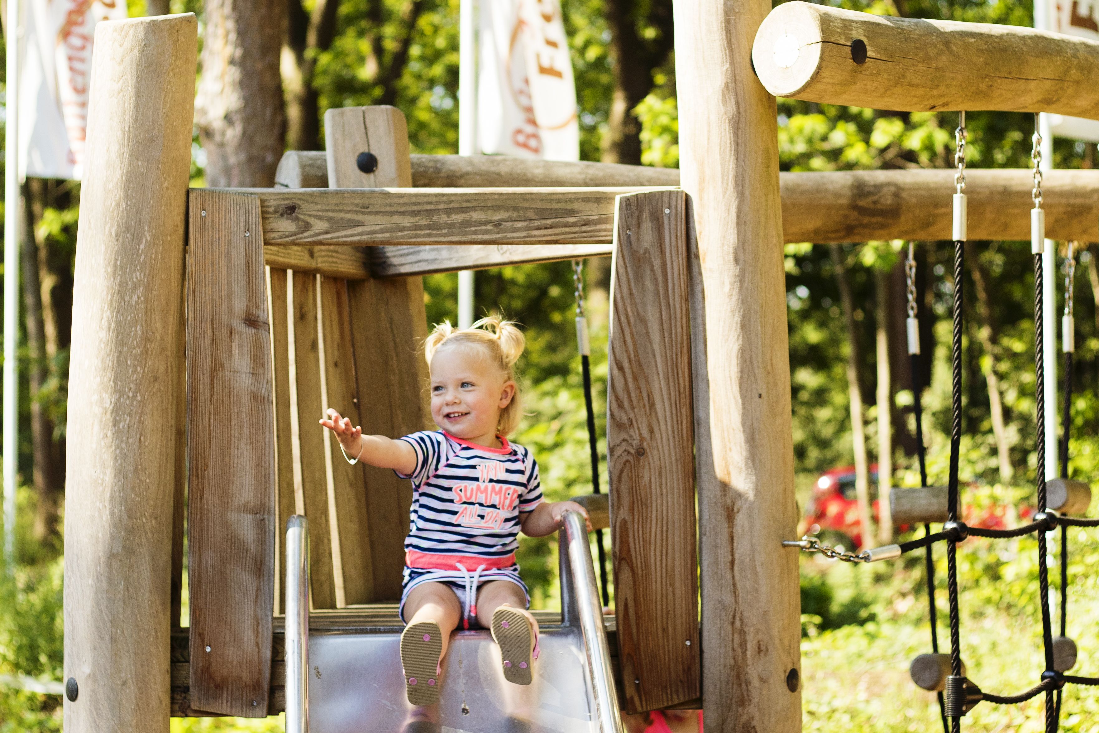 A child on a wooden slide at a playground.