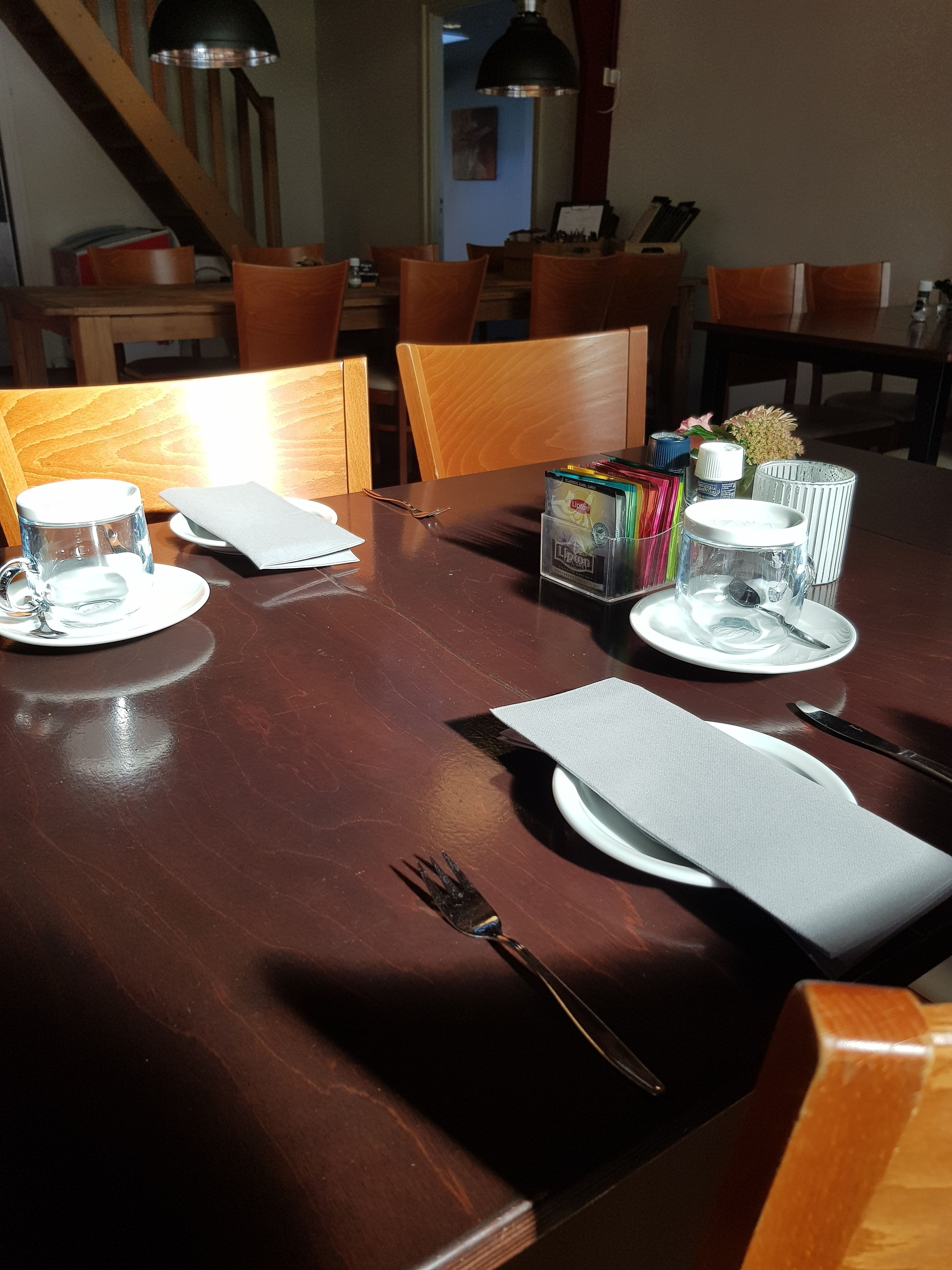 A dining table set with plates, cutlery, a glass, and a box of tissues.