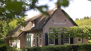A brick building with a thatched roof, a green door, and a sign reading "Hiemsheine". - Buitengoed Fredeshiem (De Bult)