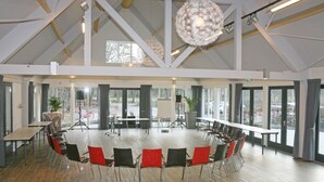 A spacious conference room with a high ceiling, large windows, and modern furniture. - Buitengoed Fredeshiem (De Bult)