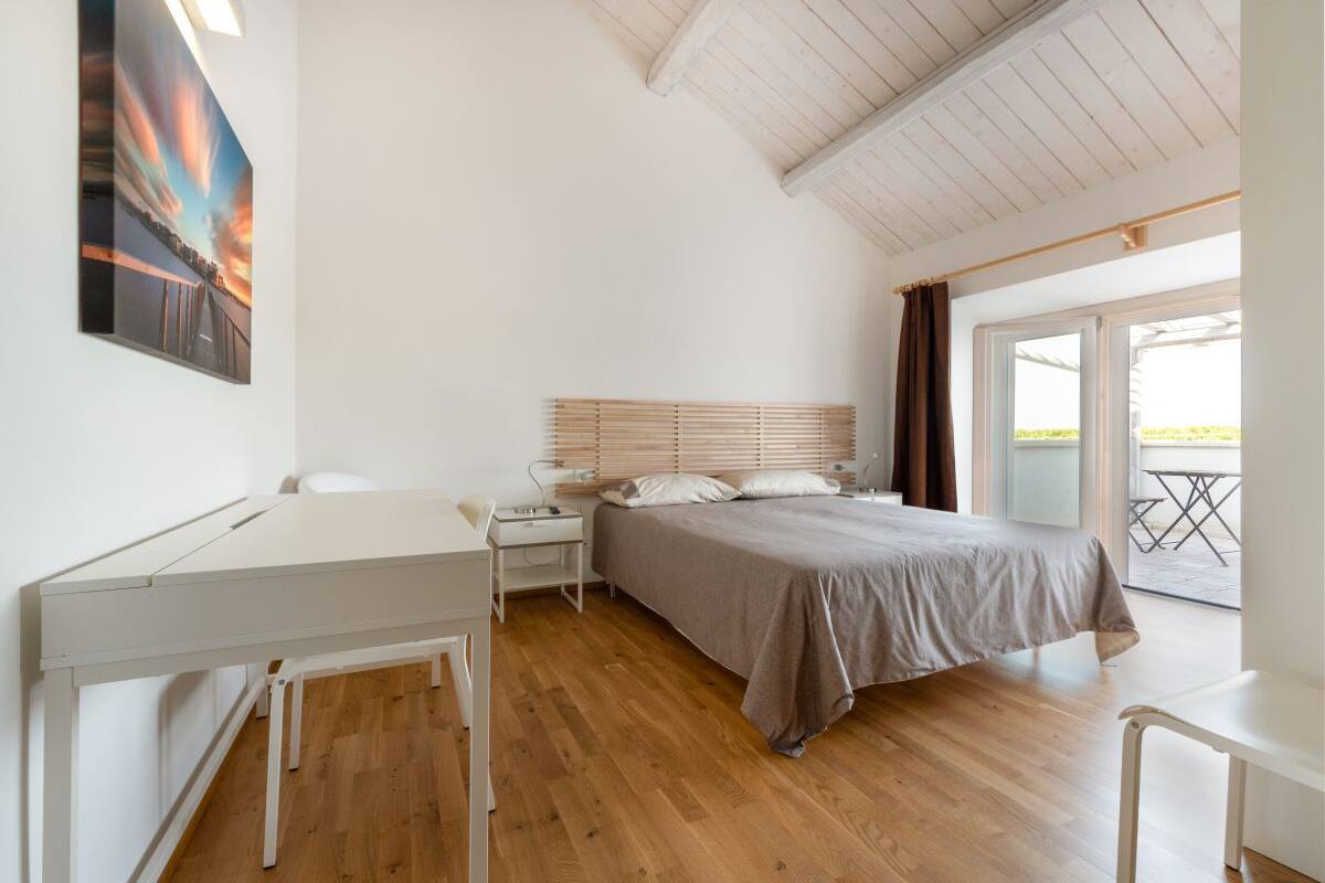 A bedroom with a bed, bedside table, and a desk.