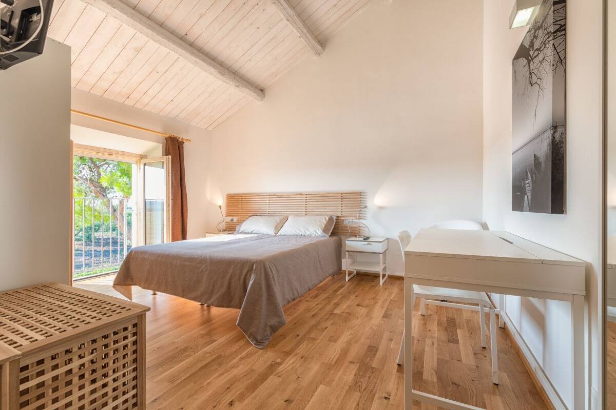 A bedroom with a bed, bedside table, and a desk.