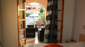 A bedroom with a bed, a second bed, a wardrobe, and a view of an outdoor balcony. - Emily's Apartments (Corfu)
