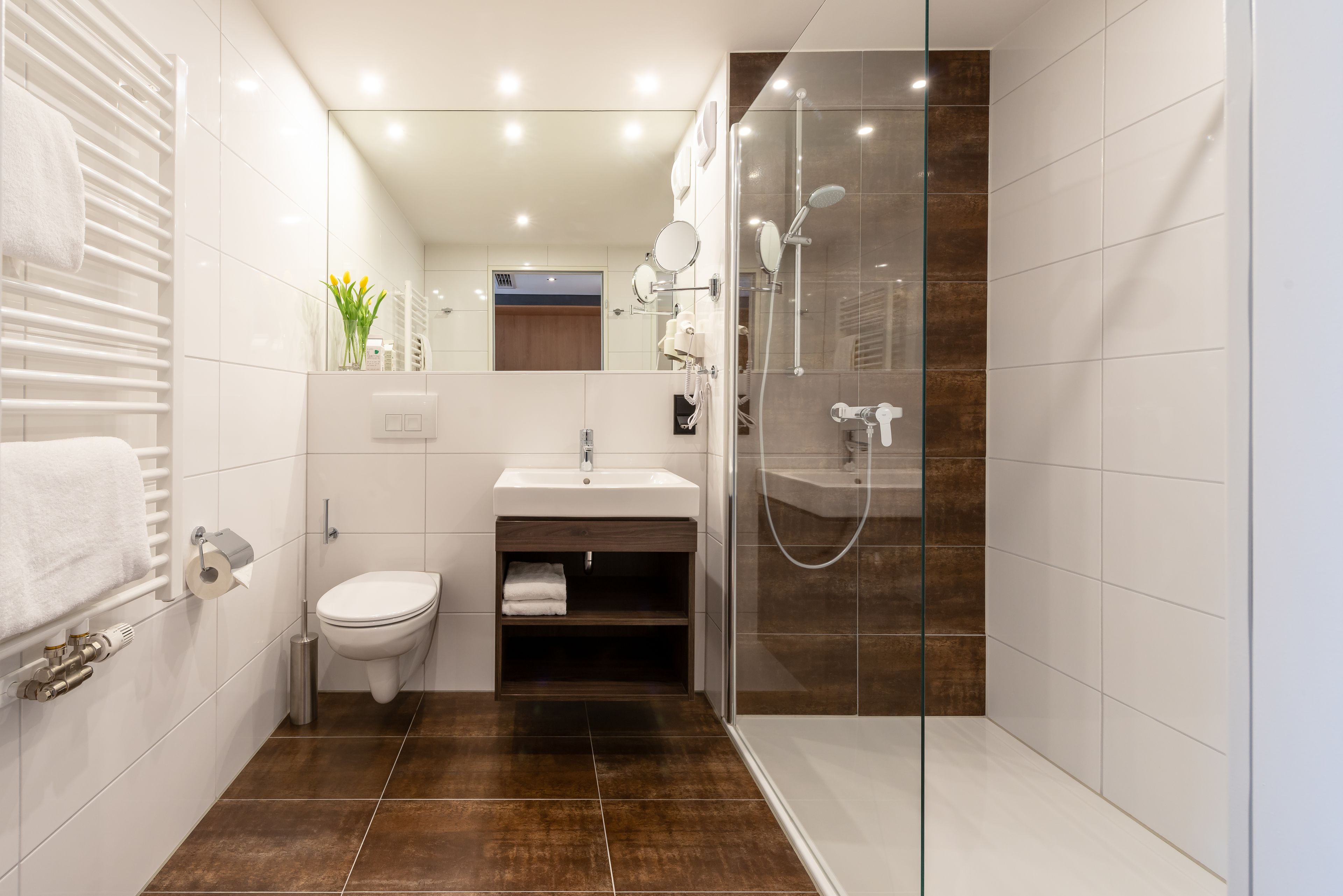 A modern bathroom with a glass-enclosed shower, a white sink, and a toilet.