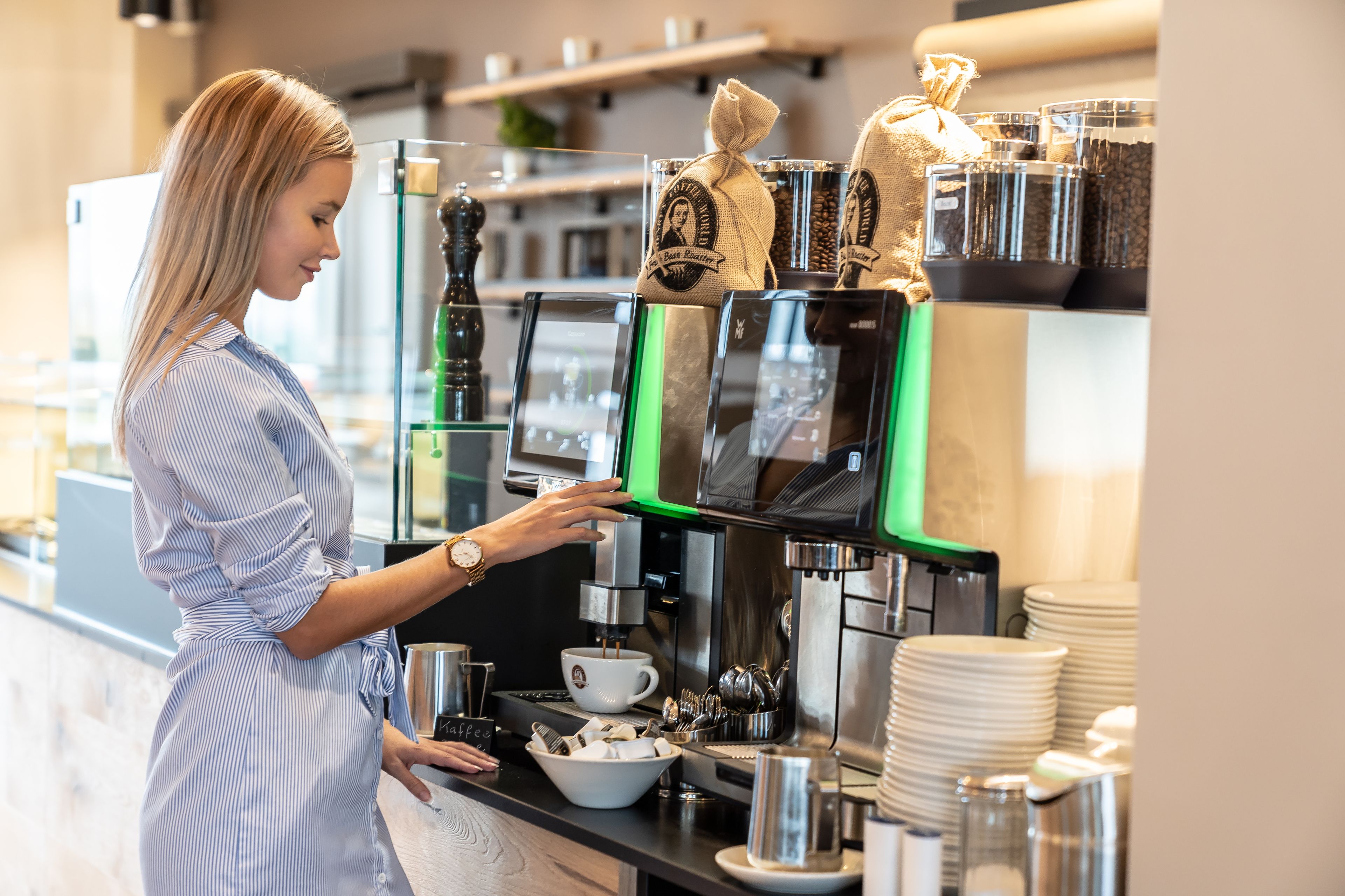 Uma pessoa manuseando uma máquina de café em uma cozinha moderna.