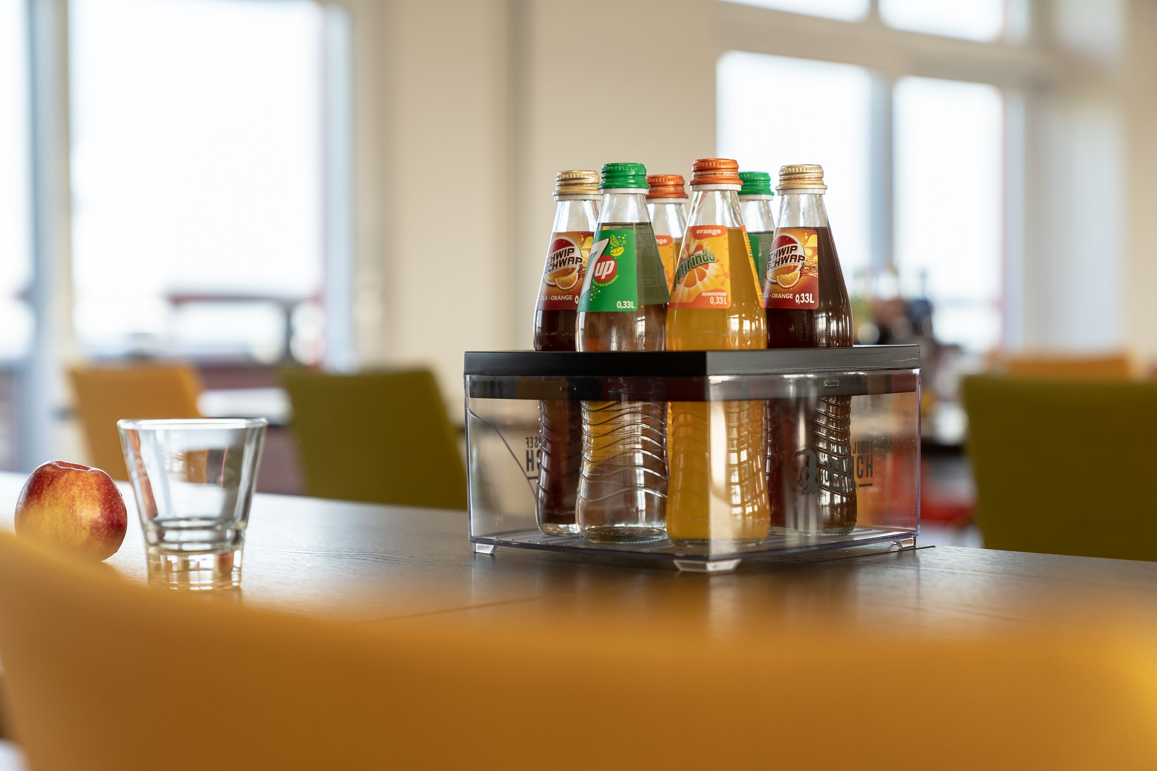 Un enfriador de bebidas con diversas opciones sobre una mesa en una habitación bien iluminada.