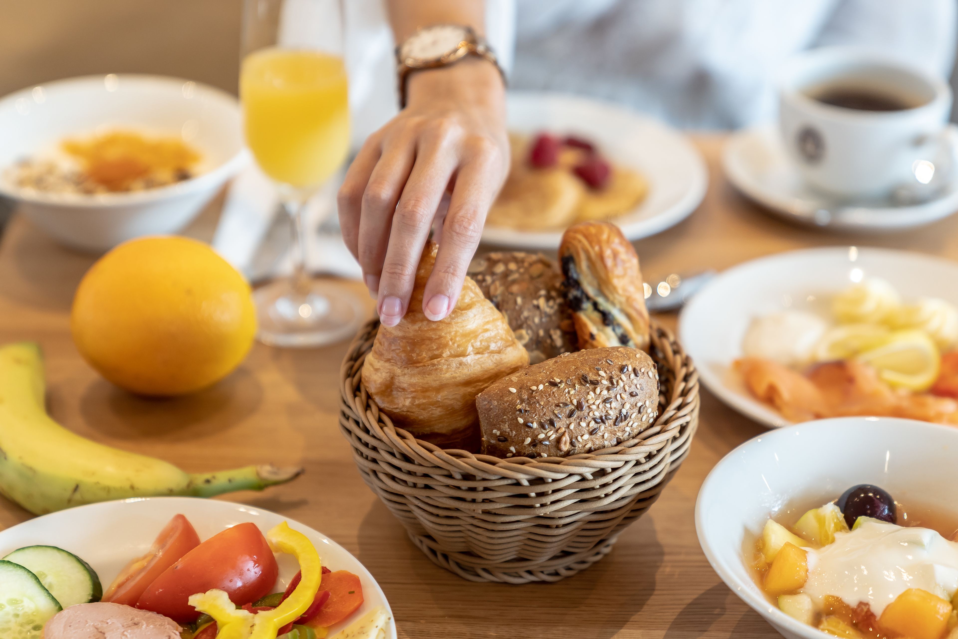 En morgenmadsopstilling med forskellige spiser og en kurv med brød.